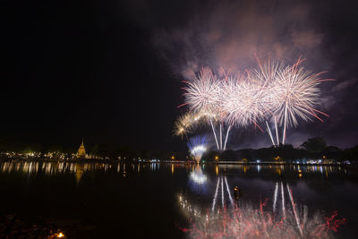 Firework display over river at night