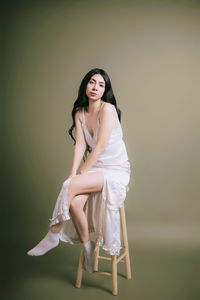 Portrait of young woman standing against wall