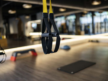 Elastic trx ropes hanging on blurred background of contemporary gym during fitness workout