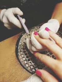 Cropped hand of nail technician doing nail art to woman fingernails