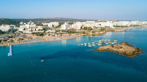 Aerial view of sea and buildings against clear sky