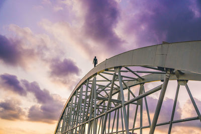 Low angle view of ferris wheel against cloudy sky