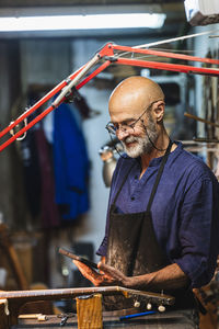 Smiling male craftsperson using digital tablet in workshop