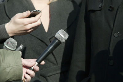 Cropped hand of journalist holding microphone for people