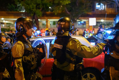 Rear view of people standing on street at night