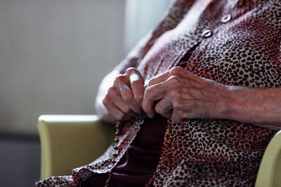 Midsection of woman holding while sitting at home