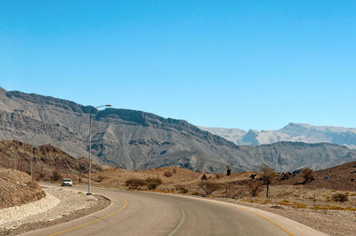 Road by mountains against clear blue sky