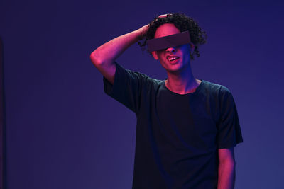 Young man wearing vr glasses against blue background