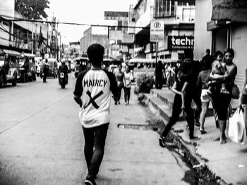 Rear view of people walking on street in city