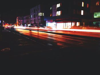 Light trails on city street by buildings at night