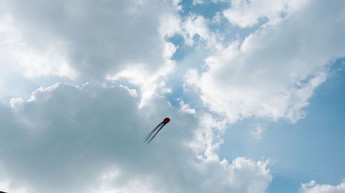 Low angle view of parachute against cloudy sky