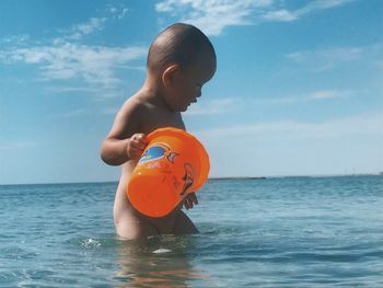 Boy in sea against sky