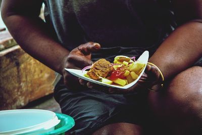 Midsection of person having food in plate