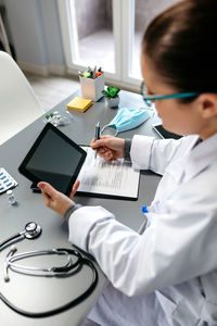 Midsection of woman using mobile phone on table