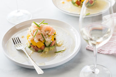 A crab stack salad served with white wine and light coming from behind.