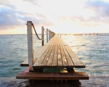 Pier over sea against sky during sunset