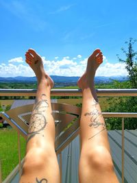 Low section of woman with tattoo relaxing on railing