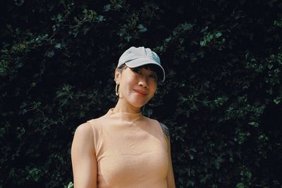 Portrait of young woman standing against plants