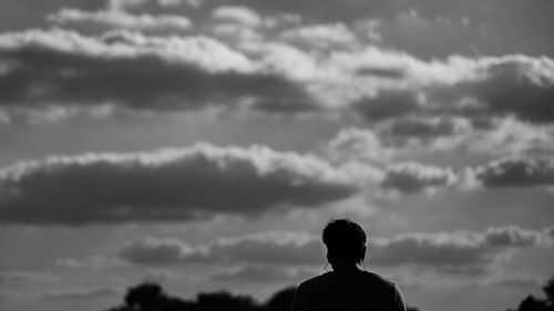 Rear view of silhouette man against cloudy sky