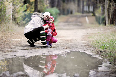 Rear view of women sitting on puddle