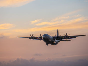 Low angle view of airplane flying against sky during sunset