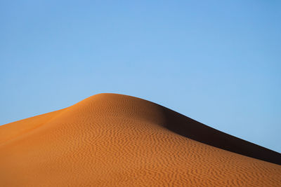 Low angle view of desert against clear blue sky