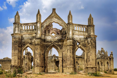 Low angle view of old ruin building against cloudy sky