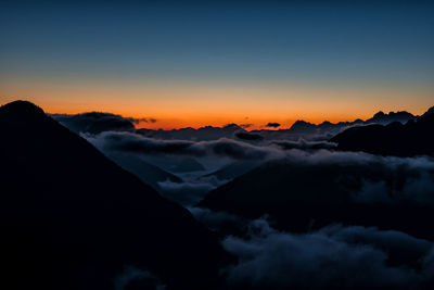 Scenic view of dramatic sky over silhouette mountains during sunset