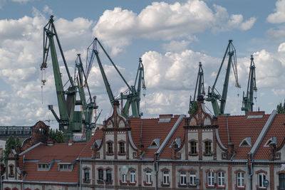 Cranes against buildings in city against sky