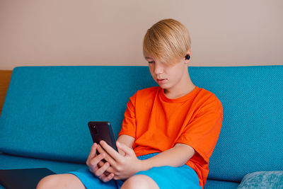Young man using mobile phone while sitting on sofa at home