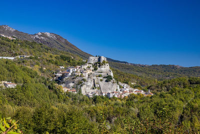 Scenic view of trees and buildings against clear blue sky