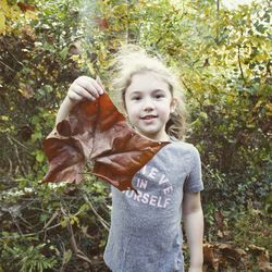 Portrait of smiling girl holding tree