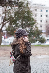 Rear view of woman standing on street in city