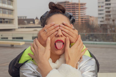 Woman covering friend eyes in city