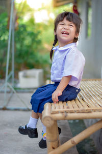 Full length of happy girl sitting outdoors