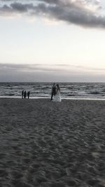 Silhouette people on beach against sky during sunset