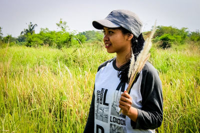 Woman looking away while standing by plants on land