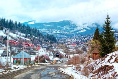 Snow covered buildings by mountain against sky