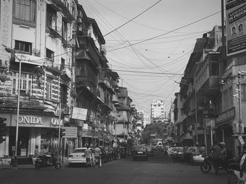 Cars on street in city against sky