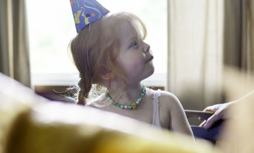 Close-up of girl wearing party hat at home