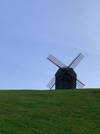 Traditional windmill on field against clear sky