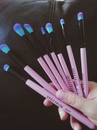 Cropped image of hand holding various make-up brushes