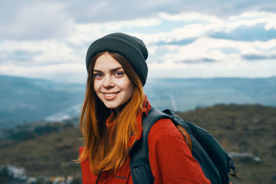 Portrait of smiling young woman standing against sky during winter