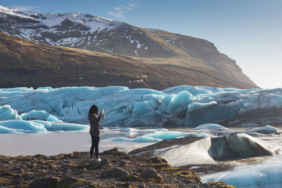 Man standing on rock by snowcapped mountains during winter