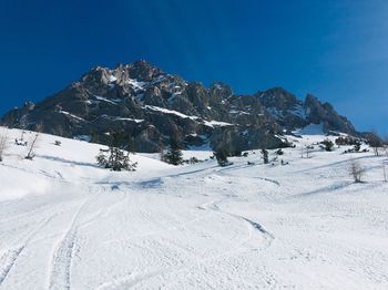 Scenic view of snow covered mountains against blue sky