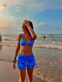 Rear view of woman standing at beach