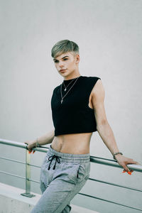 Young woman looking away while standing against wall