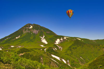 Hot air balloons flying over mountains against sky