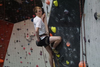 Side view of man climbing on artificial wall
