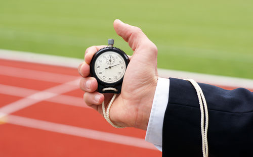 Cropped image of hand holding clock against blurred background